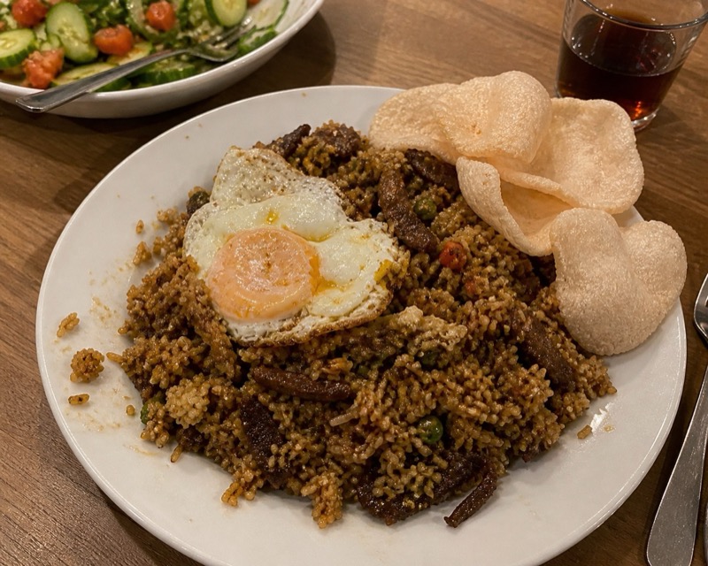 Nasi goreng met gebakken ei en kroepoek op een bord thuis aan tafel