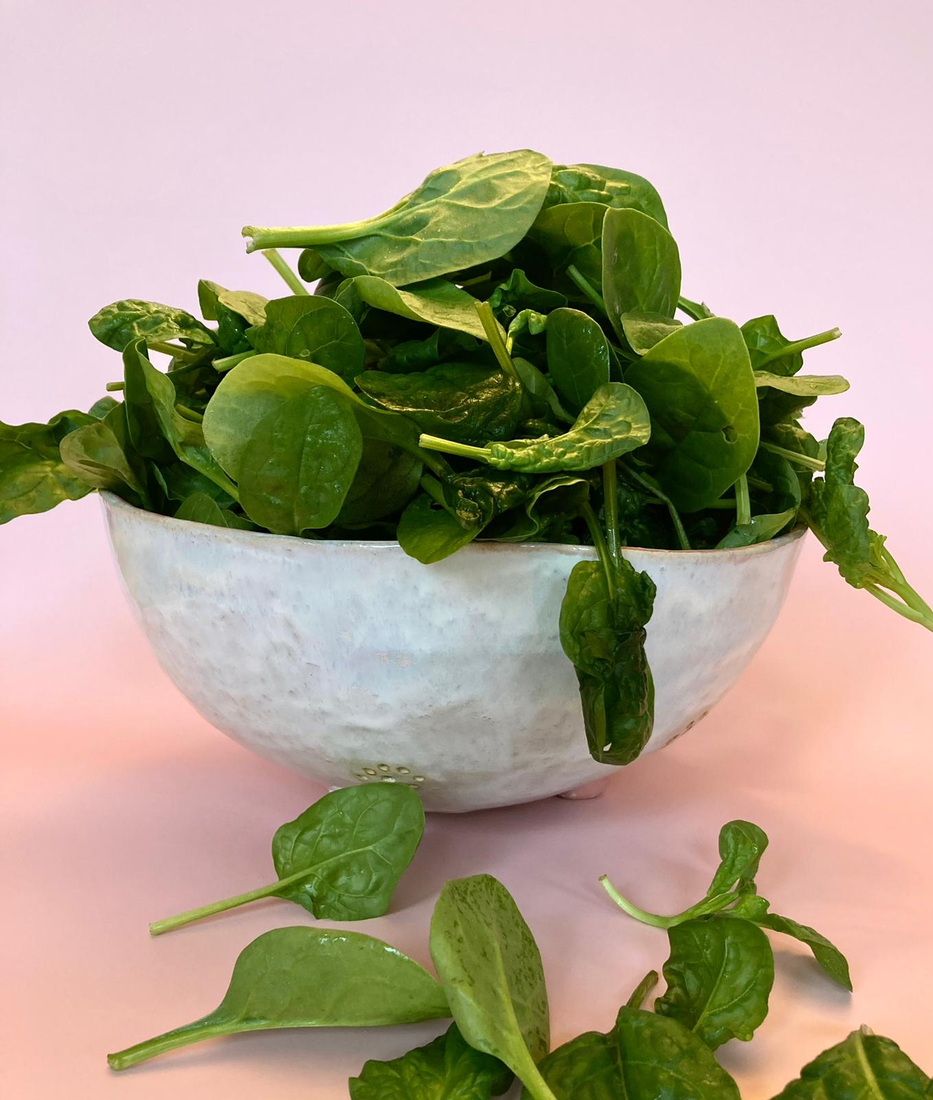 Fresh spinach leaves in a white ceramic bowl
